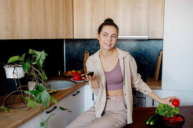 Una joven prepara ensalada de verduras en casa Cocina vegana