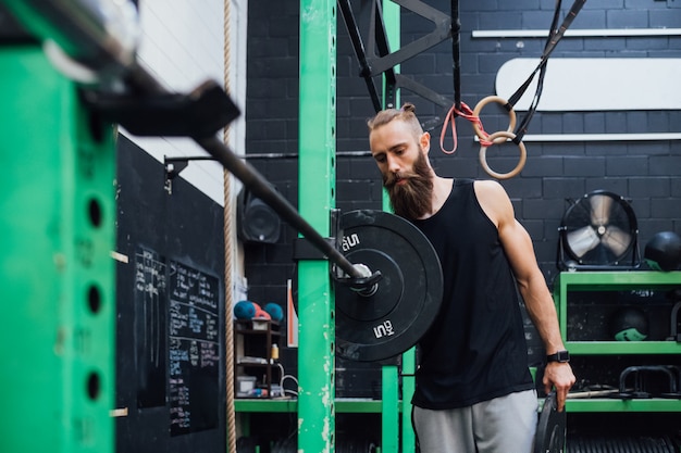 Joven preparando pesas gimnasio entrenamiento