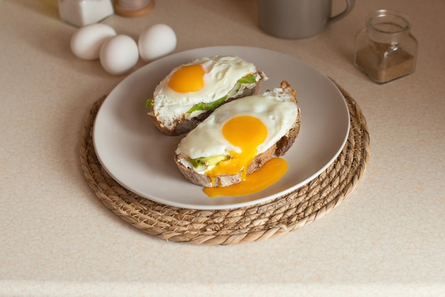 Joven preparando tostadas con aguacate y huevo para desayunar en la cocina