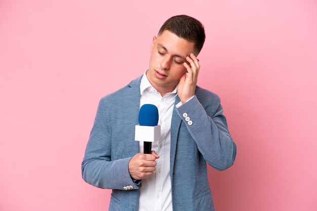 Joven presentador brasileño hombre aislado sobre fondo rosa con dolor de cabeza