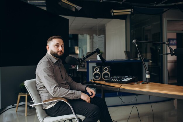 Joven presentador de radio sonriente hablando en un micrófono y transmitiendo en el concepto de entretenimiento y comunicación del estudio