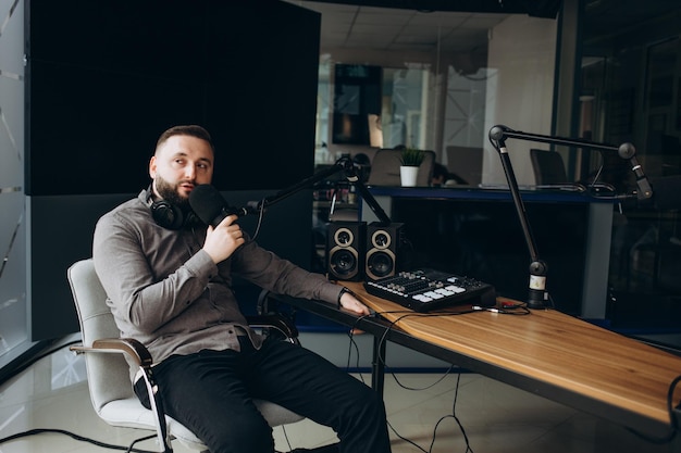 Joven presentador de radio sonriente hablando en un micrófono y transmitiendo en el concepto de entretenimiento y comunicación del estudio