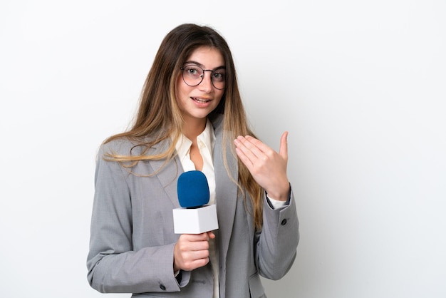 Joven presentadora de televisión caucásica mujer aislada de fondo blanco invitando a venir con la mano Feliz de que hayas venido