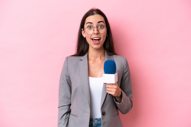 Joven presentadora de televisión caucásica mujer aislada sobre fondo rosa con expresión facial sorpresa
