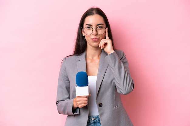 Joven presentadora de televisión caucásica mujer aislada sobre fondo rosa pensando en una idea