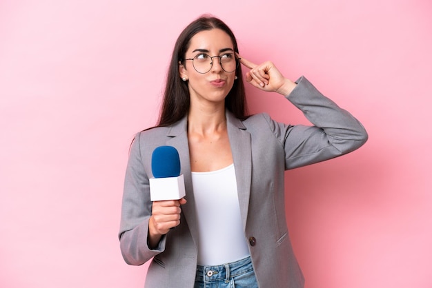 Joven presentadora de televisión caucásica mujer aislada sobre fondo rosa que tiene dudas y pensamiento