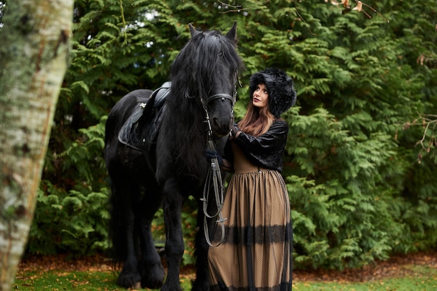 Una joven princesa con un vestido vintage con ternura y amor abraza a su caballo