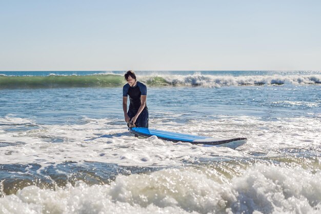 Joven, principiante Surfer aprende a surfear en una espuma de mar en la isla de Bali