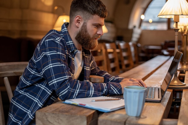 Joven profesional navegando por internet en su computadora portátil en un café