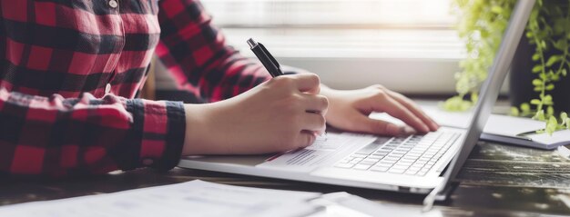 Joven profesional trabajando en una computadora portátil con bloc de notas