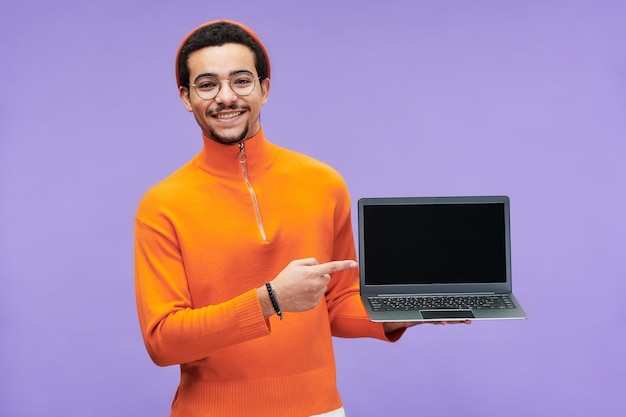 Joven programador exitoso apuntando a la pantalla en blanco de la computadora portátil