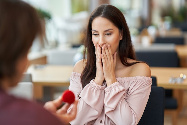 joven proponiendo a su novia en un café