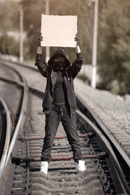 Una joven protestante se encuentra en la vía férrea, sosteniendo un cartel con la inscripción encima de ella.