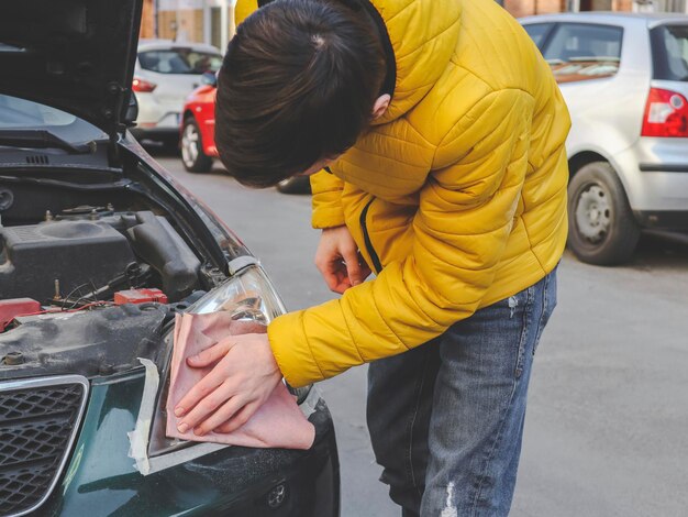 Joven puliendo un faro con un trapo