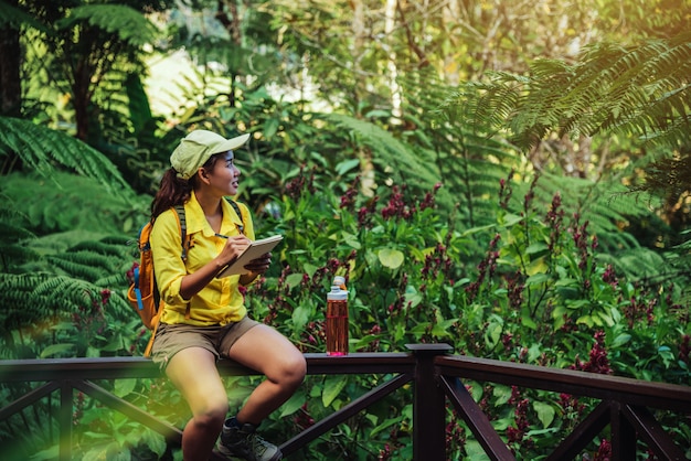 Foto la joven que está sentada escribiendo, grabando y estudiando la naturaleza del bosque.