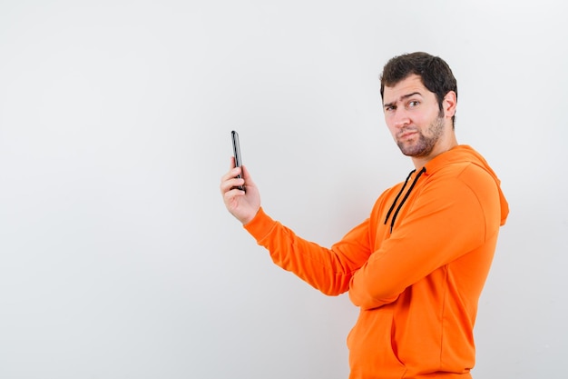 El joven que sostiene el teléfono móvil muestra un mimetismo divertido en el fondo blanco