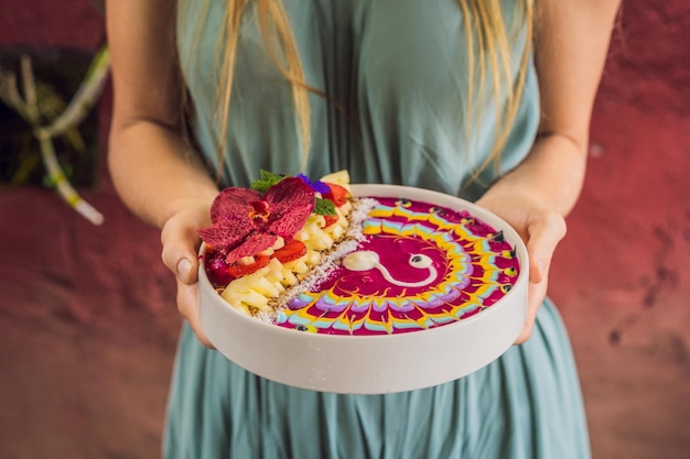 Foto una joven que tiene un desayuno mediterráneo come un tazón de batido de desayuno tropical saludable con