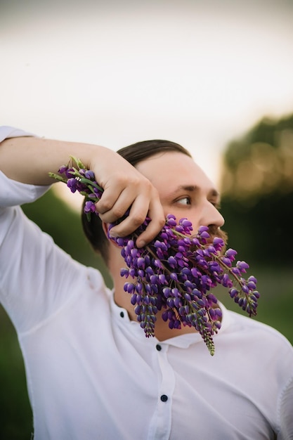 Foto joven con ramo de lupinos como una barba puesta de sol o amanecer luz brillante de la tarde