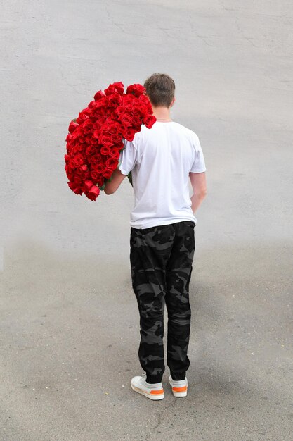 Joven con un ramo de rosas rojas en la calle