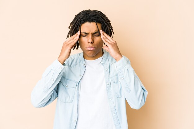 Joven rasta afroamericano tocando las sienes y teniendo dolor de cabeza.