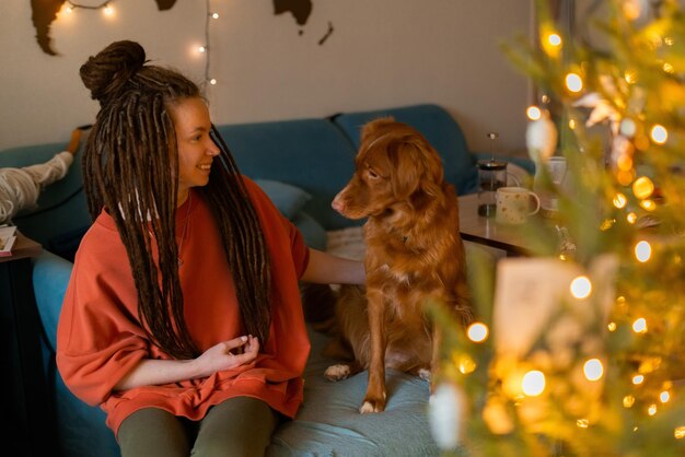 Una joven con rastas pasa tiempo con su perro de peaje en casa durante las vacaciones