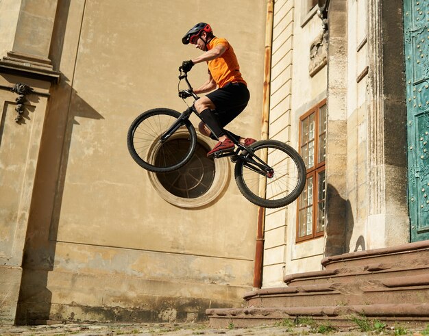 Foto joven realizando saltos radicales en bicicleta de montaña en el casco antiguo