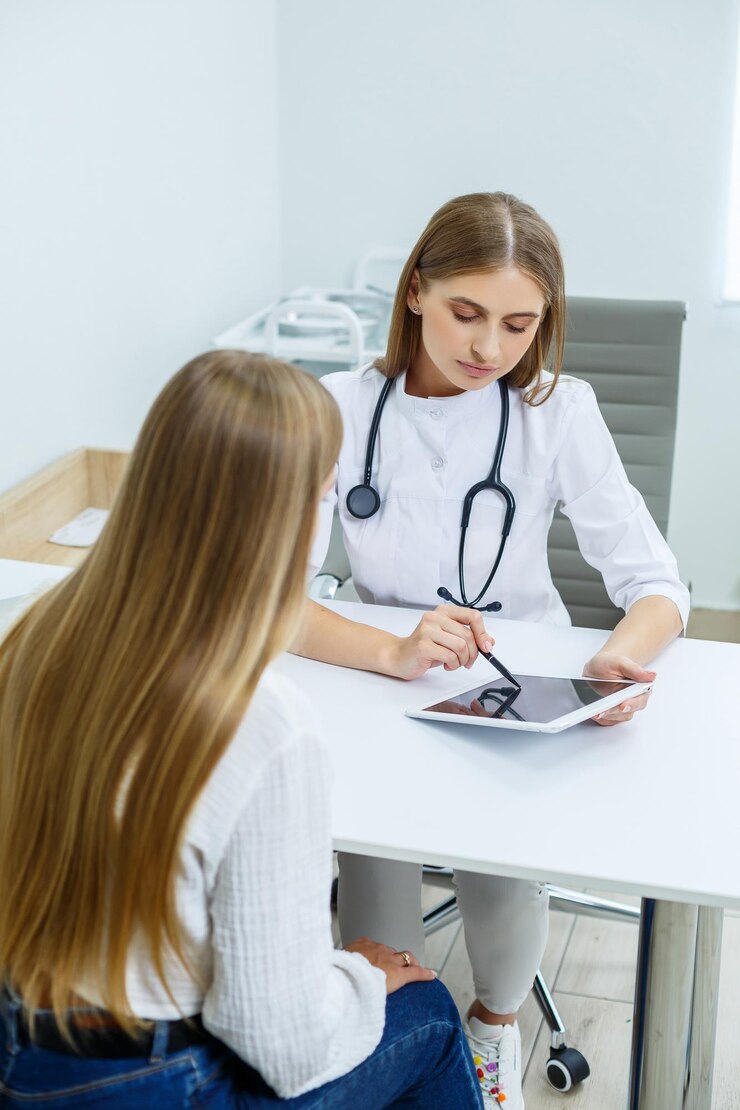 Una joven en la recepción de una doctora especialista Terapeuta realiza un examen preventivo de una joven en su oficina en una clínica moderna