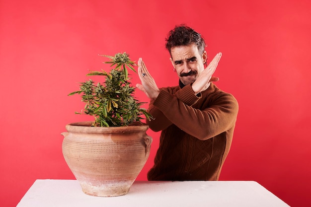 Un joven rechazando una planta de marihuana con antecedentes rojos.