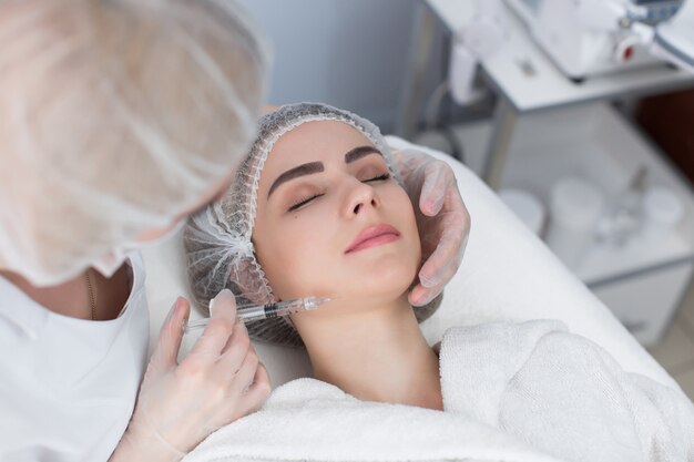 Joven recibe inyecciones faciales de belleza en salón