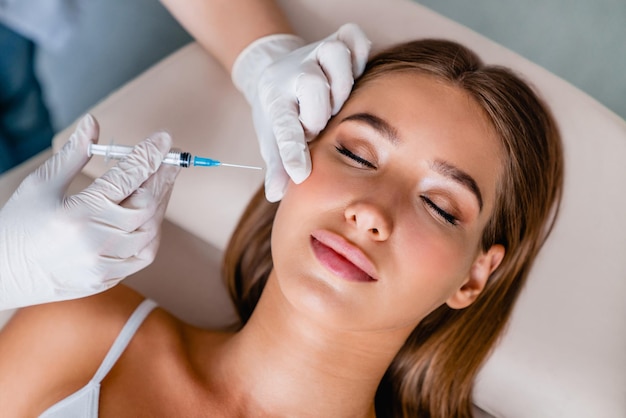 Foto joven recibe inyecciones faciales de belleza en salón