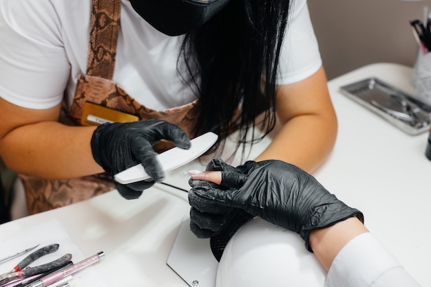 Una joven recibe una manicura de primer plano en sus manos en un salón de belleza.