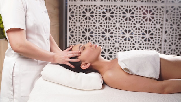 Joven recibe un masaje relajante en la cabeza en un salón de belleza