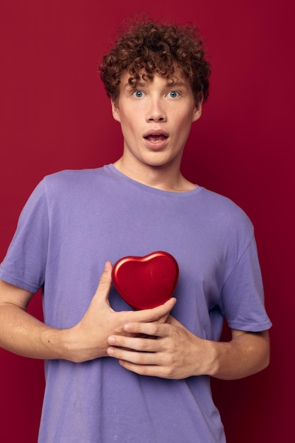 Joven regalo en forma de corazón fondo rojo.