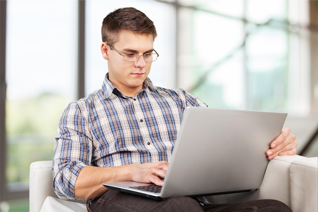 Joven relajándose en el sofá con una laptop