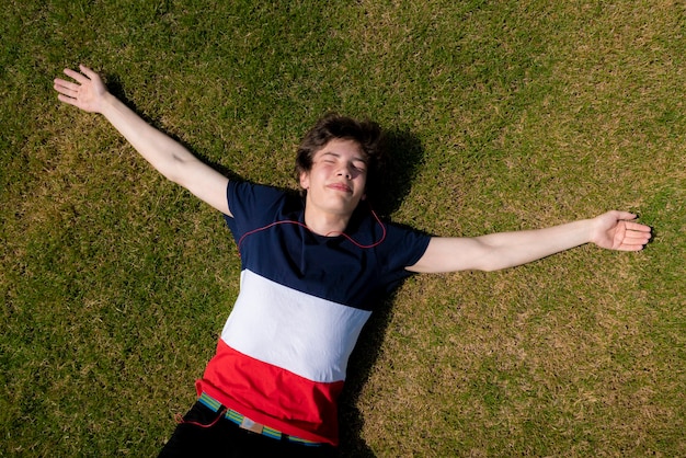 Joven relajarse al aire libre en el césped de hierba verde bajo los rayos del sol de verano