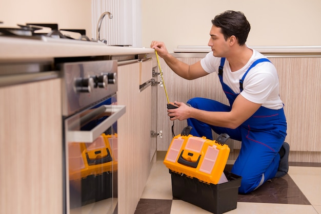 Joven reparador trabajando en la cocina