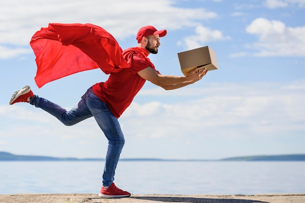 Foto joven repartidor con capa de superhéroe