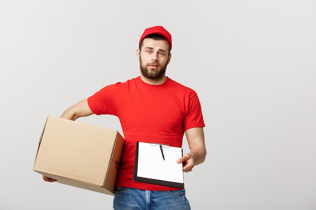 Joven repartidor guapo con cajas de papel que le da un documento para firmar