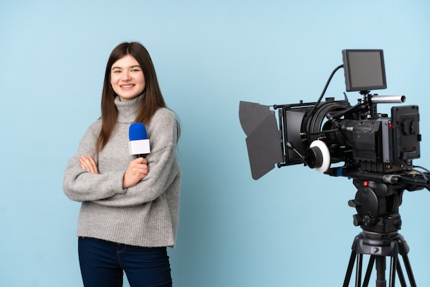 Joven reportero mujer sosteniendo un micrófono y reportando noticias riendo