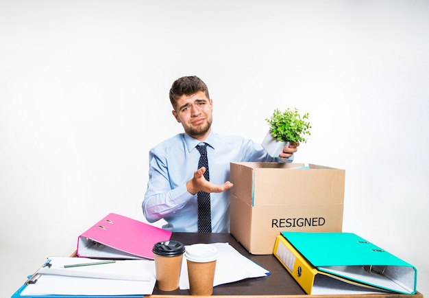 El joven se resigna y dobla cosas en el lugar de trabajo, carpetas, documentos. No podía hacer frente a las responsabilidades. Concepto de problemas de oficinista, negocios, publicidad, problemas de resignación.