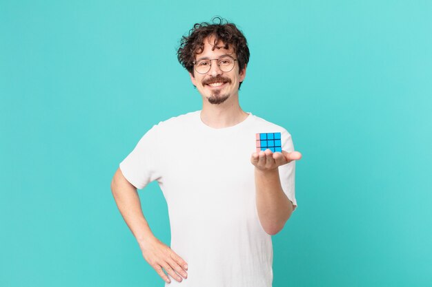 Joven resolviendo un problema de inteligencia sonriendo felizmente con una mano en la cadera y confiado