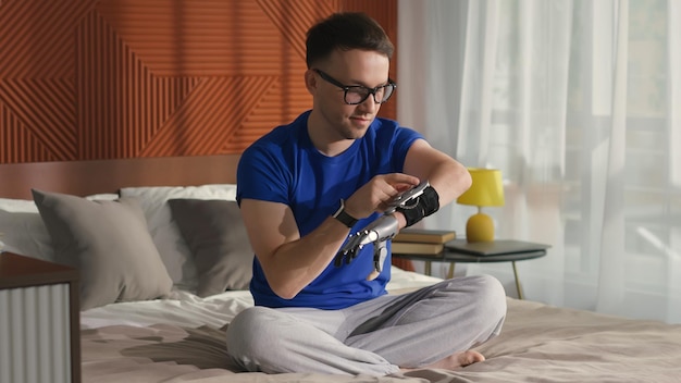 Joven revisa la hora o usa internet en un dispositivo de brazo biónico sentado en la cama