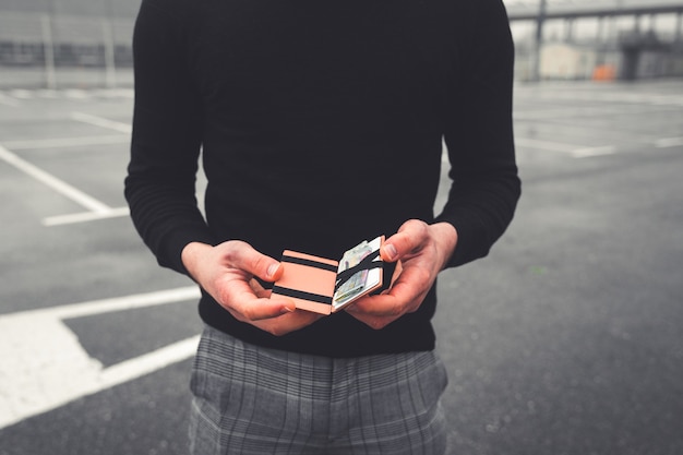 Joven revisando una billetera con tarjetas y euros