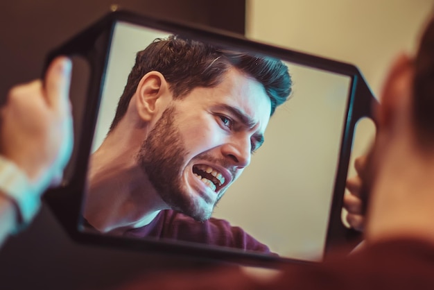 Joven revisando sus dientes en el espejo después del tratamiento dental - Concepto de cuidado corporal y estomatología de personas para un estilo de vida saludable - Centrarse en la cara del hombre -