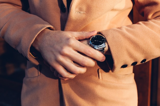 Joven revisando el tiempo en un elegante reloj de mano mecánico de metal Accesorios masculinos