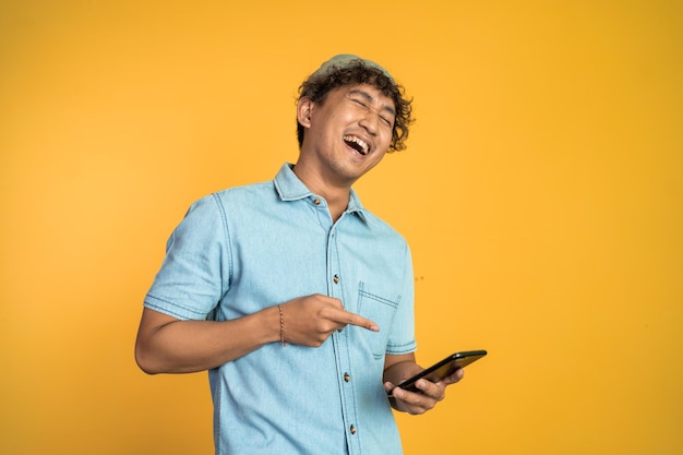 El joven se ríe mucho cuando mira un teléfono móvil