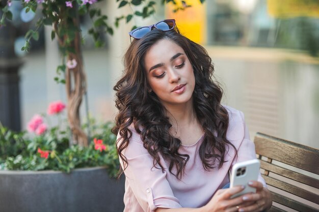 Una joven rizada usa un teléfono para las redes sociales Una modelo se toma una selfie en la calle de una ciudad europea en verano Videollamada