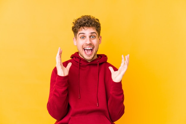 joven rizado feliz sobre pared amarilla