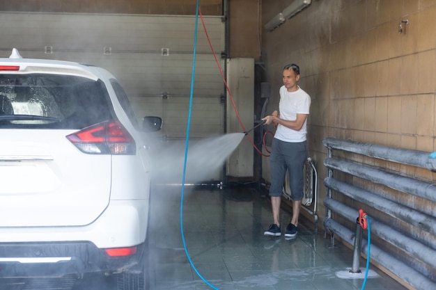 Joven rociando su auto limpio