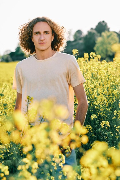 Un joven rodeado de flores amarillas en un soleado día de primavera